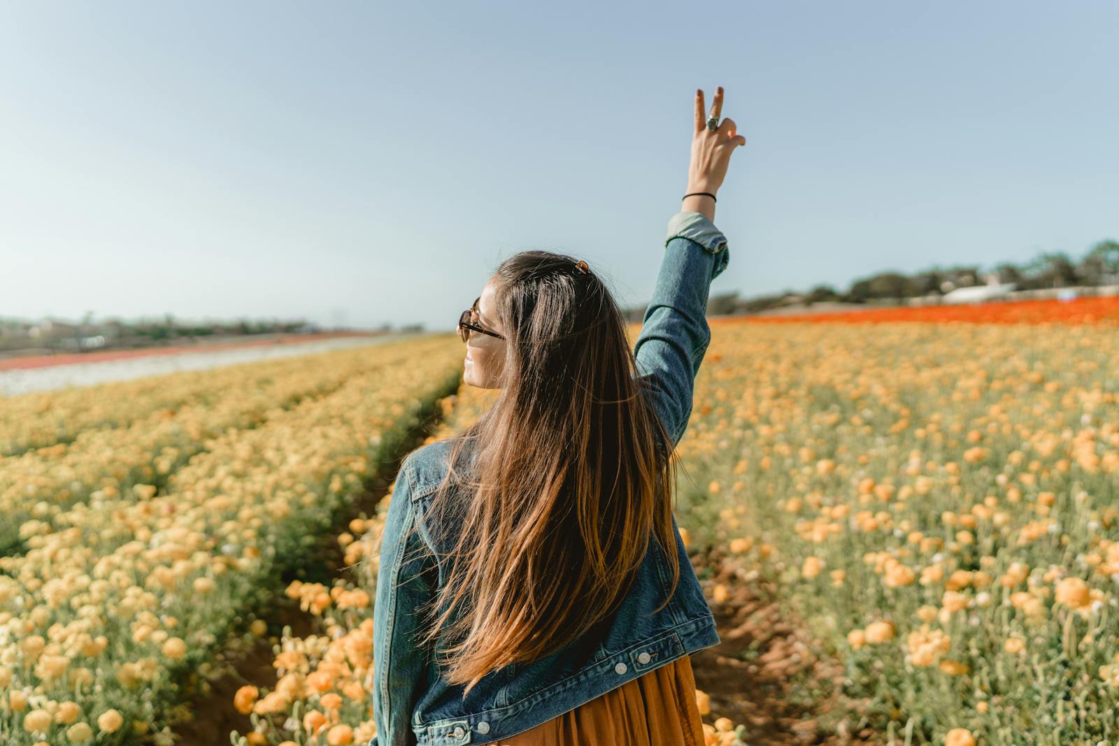 A woman enjoying a sunny day in a vivid yellow flower field in Carlsbad, CA.