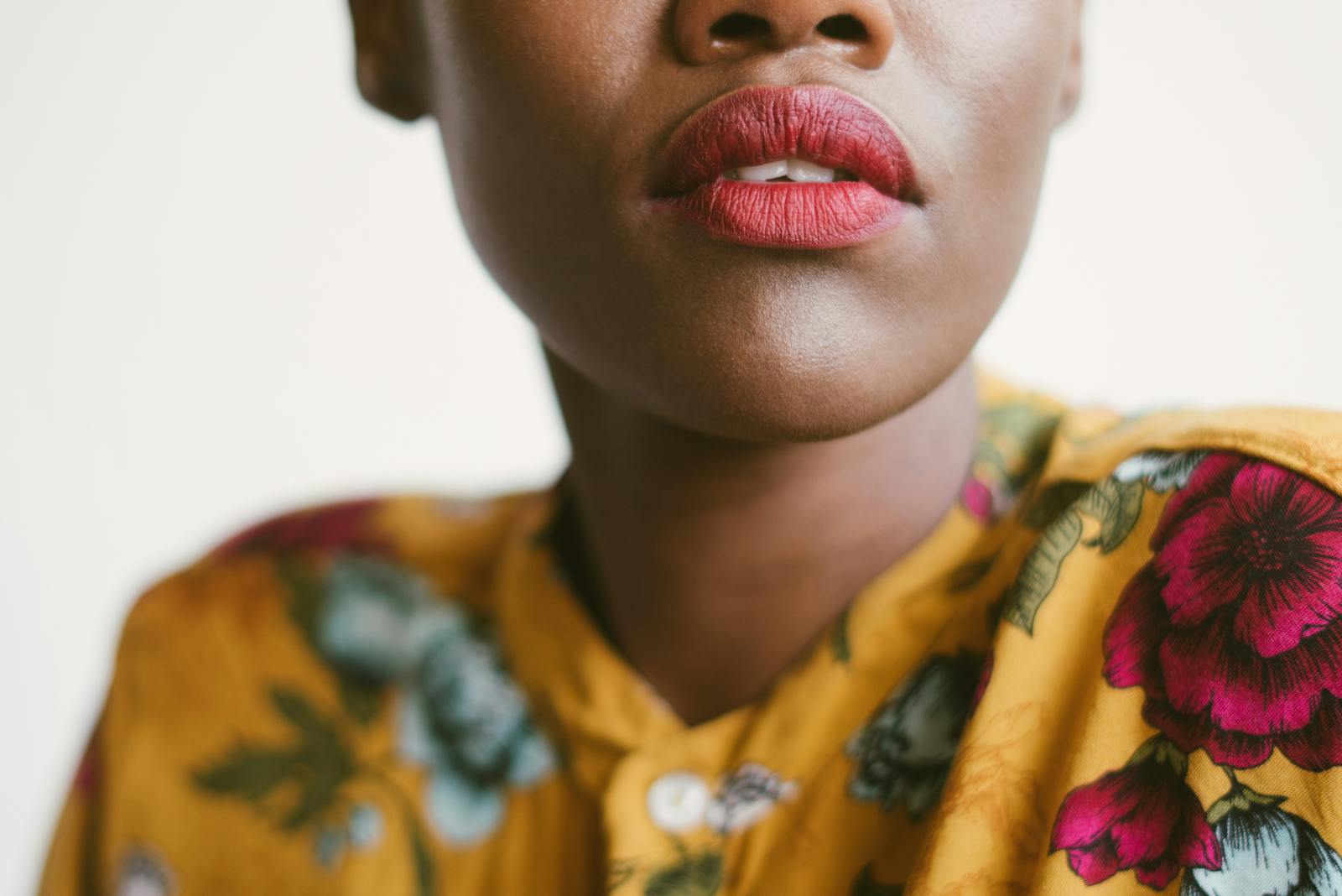 A close-up of a woman with red lips wearing a floral-patterned outfit, exuding style and elegance.