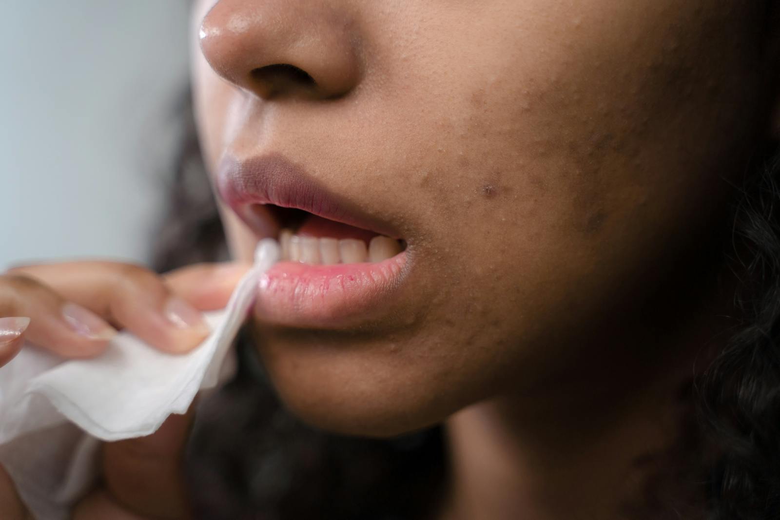 Detailed close-up of a woman wiping her lips, showing skin texture and care.